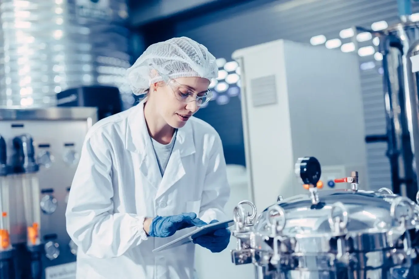 Operators at stainless steel mixing tank in batch manufacturing, process analytical technology.